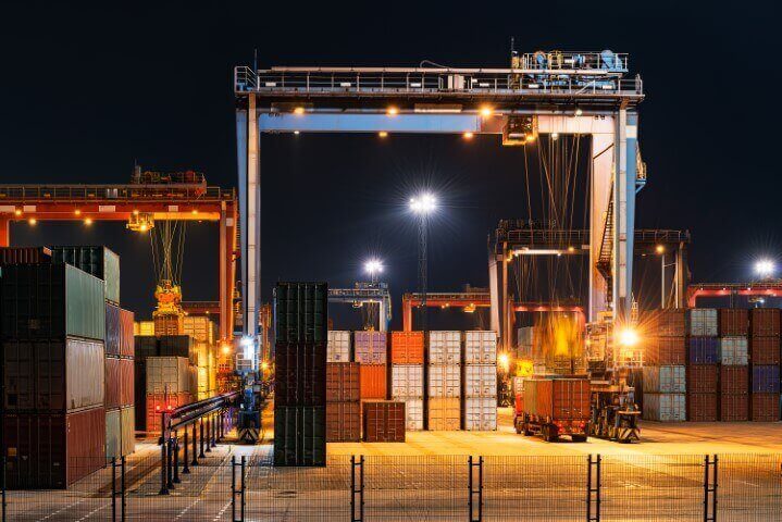Shipping containers and cranes at a port at night