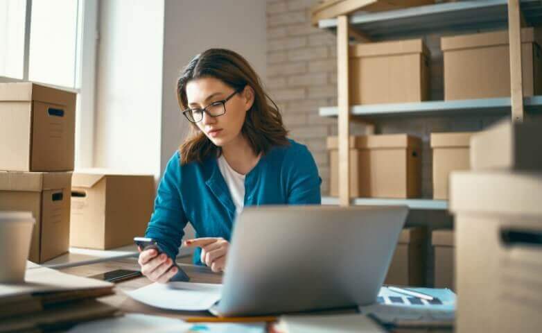 Woman working at a laptop in a warehouse for an online store